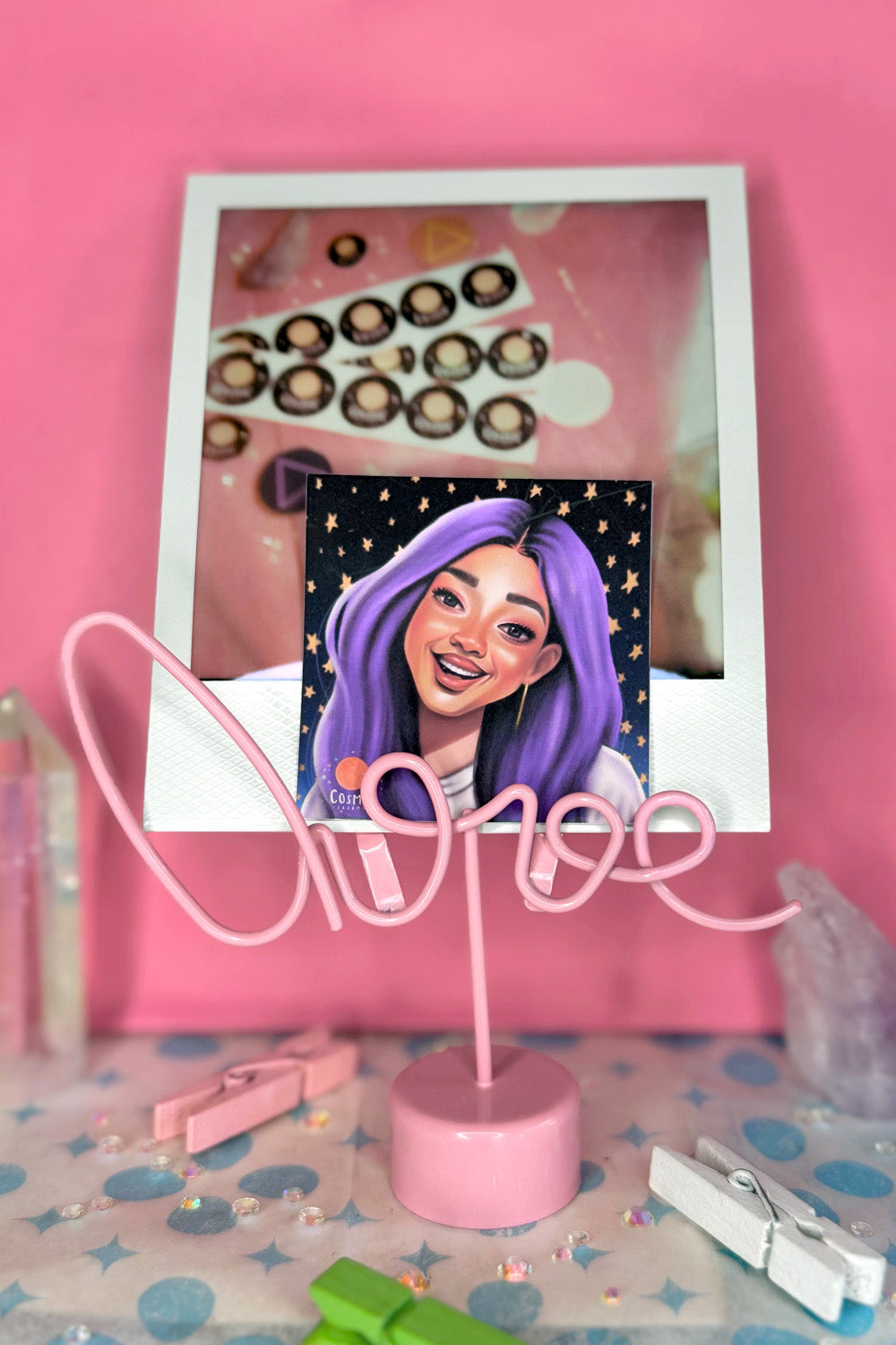Sticker of Celeste Estrella smiling with long pastel purple hair on a black starry background. Styled with a pink and crystal setup.