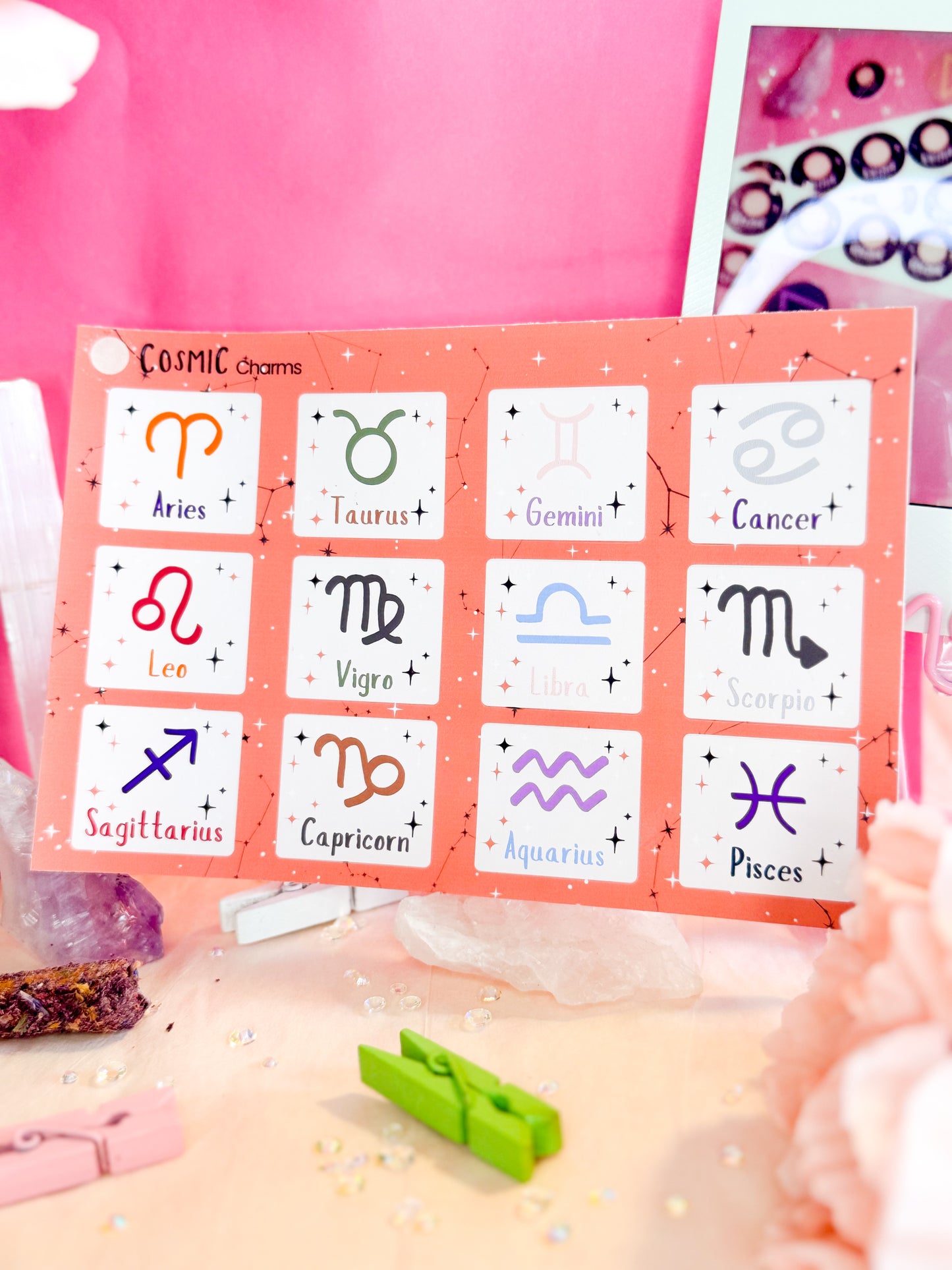Crystals holding a Zodiac Symbols sticker sheet featuring colorful astrology icons for planners and journals